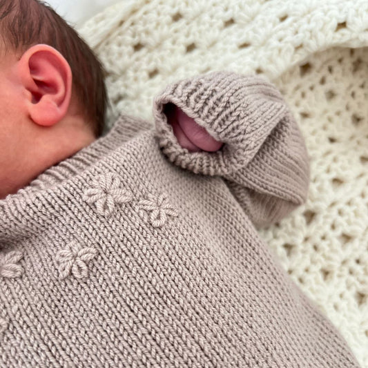 Detaljer på broderte blomster på strikket baby body – kan strikkes med eller uten broderte blomster. Strikkepakke blomsterbody i 100% merinoull med enkel strikkeoppskrift – nybegynnervennlig babystrikk. Lettstrikket body med elastisk hals for lett av- og påkledning.