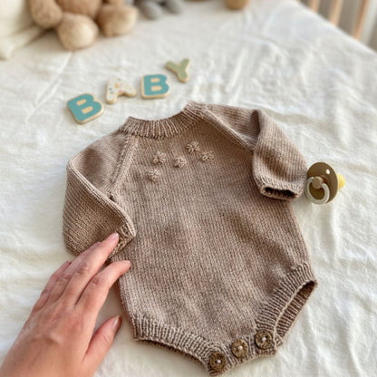 Strikket blomsterbody i sand – lettstrikket body i 100% merinoull med broderte blomster. Strikkepakke baby body med elastisk hals for lett av- og påkledning og knapper mellom beina for enkelt bleiebytt. Nybegynnervennlig babystrikk i mange farger.