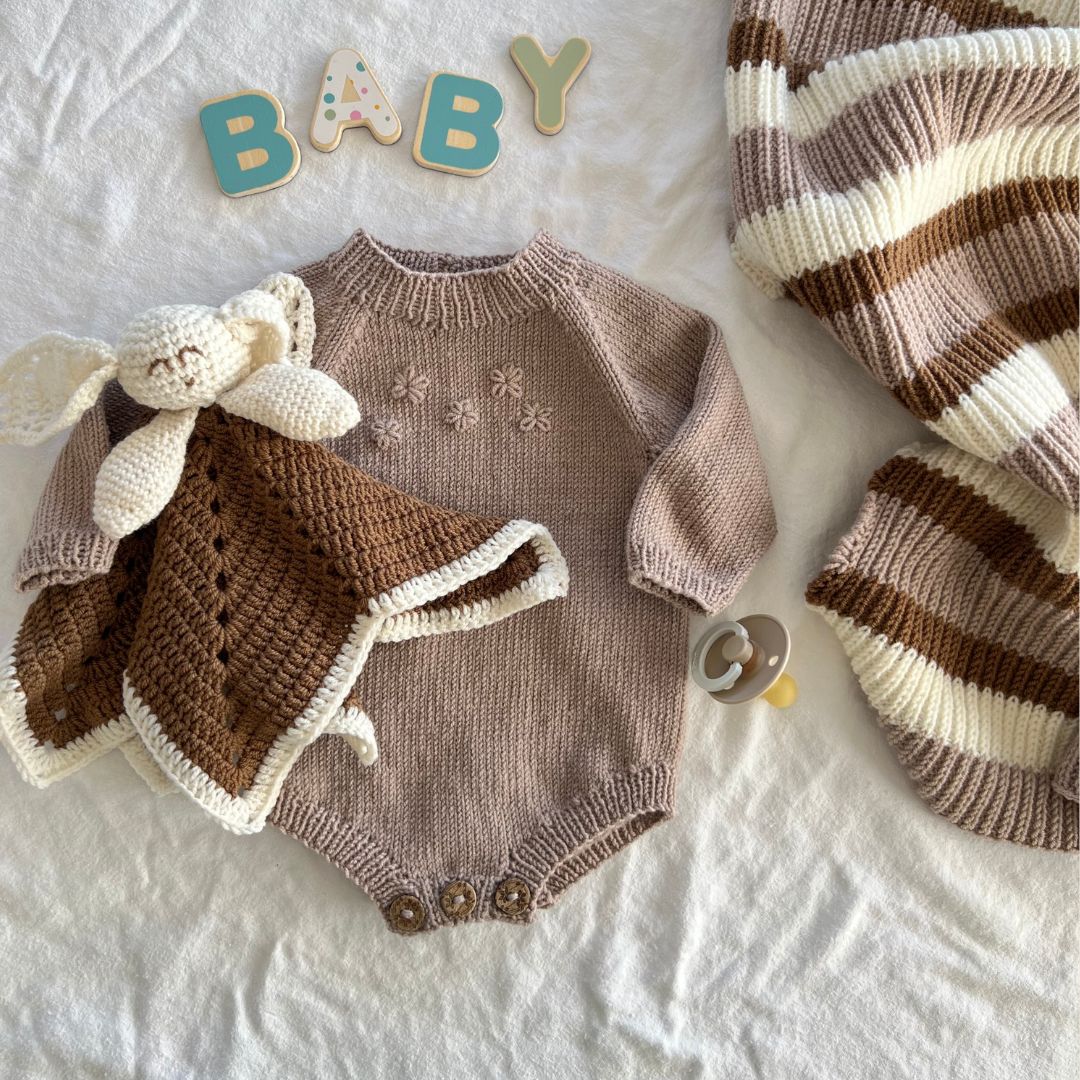 Strikket blomsterbody med koseklut og yndlingspledd – strikke babygarderoben i 100% kløfri merinoull. Lettstrikket body som perfekt første babystrikk – strikkepakke blomsterbody med enkel strikkeoppskrift. Body er det mest brukte babyplagget – nybegynnervennlig babystrikk.