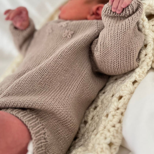 Strikket baby body sett fra siden – lettstrikket body i 100% merinoull med elastisk hals for lett av- og påkledning. Strikkepakke blomsterbody med enkel strikkeoppskrift – nybegynnervennlig babystrikk. Body er det mest brukte babyplagget – strikk den selv i kløfri merinoull.