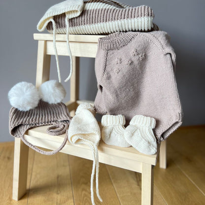 Strikket blomsterbody sammen med flere strikkede plagg – strikke babygarderoben i 100% kløfri merinoull. Strikkepakke blomsterbody med enkel strikkeoppskrift – nybegynnervennlig babystrikk. Lettstrikket body med knapper mellom beina for enkelt bleiebytt og elastisk hals for lett av- og påkledning