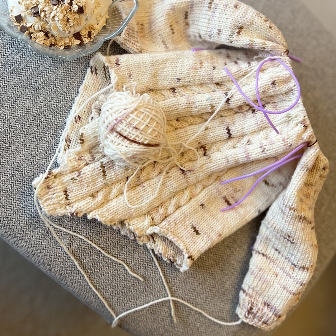 Vesleskattens flettebody på pinnene – strikkepakke baby body i håndfarget eksklusivt Unikt Garn med flettemønster. Størrelser fra nyfødt til 2,5 år, elastisk hals og knapper mellom beina for enkelt bleiebytt.
