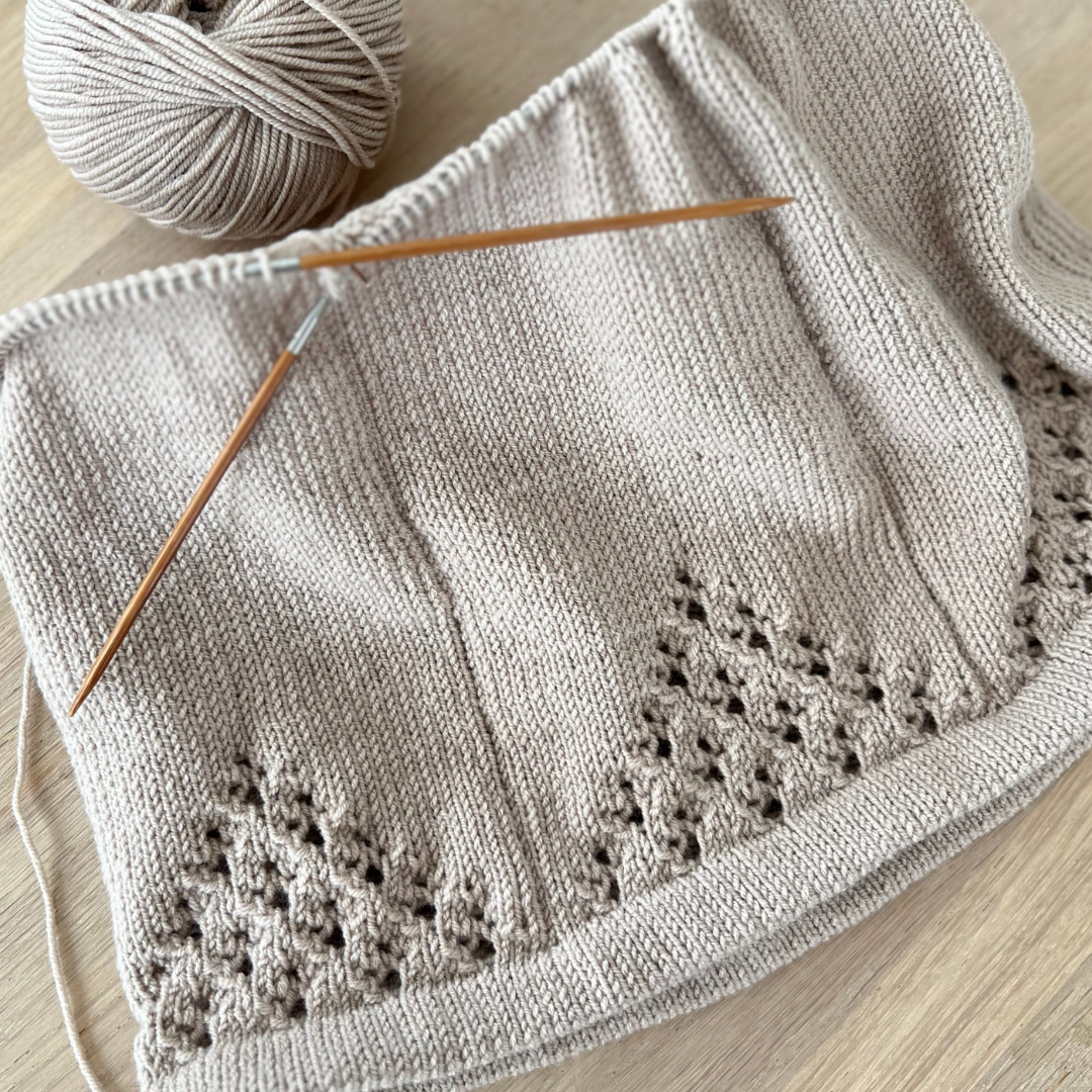 Strikkepakke kjole til baby. Kjolen strikkes nedenfra og opp med hullmønster. Strikkepakke til baby og småbarn.