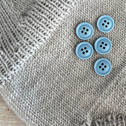 Lyseblå knapper fra Go Handmade som selges enkeltvis. Perfekt til babystrikk. 15 mm diameter. Laget av resin.