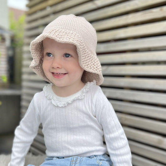 Barn med strikket solhatt – strikkeoppskrift til baby og barn 6 måneder til 6 år