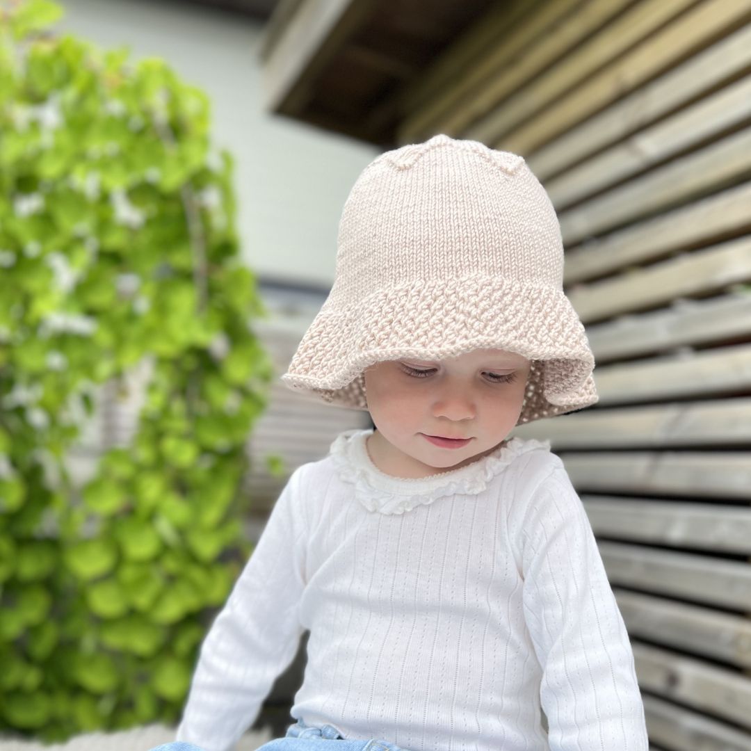 Barn med strikket solhatt – nybegynnervennlig oppskrift uten garn baby og barn