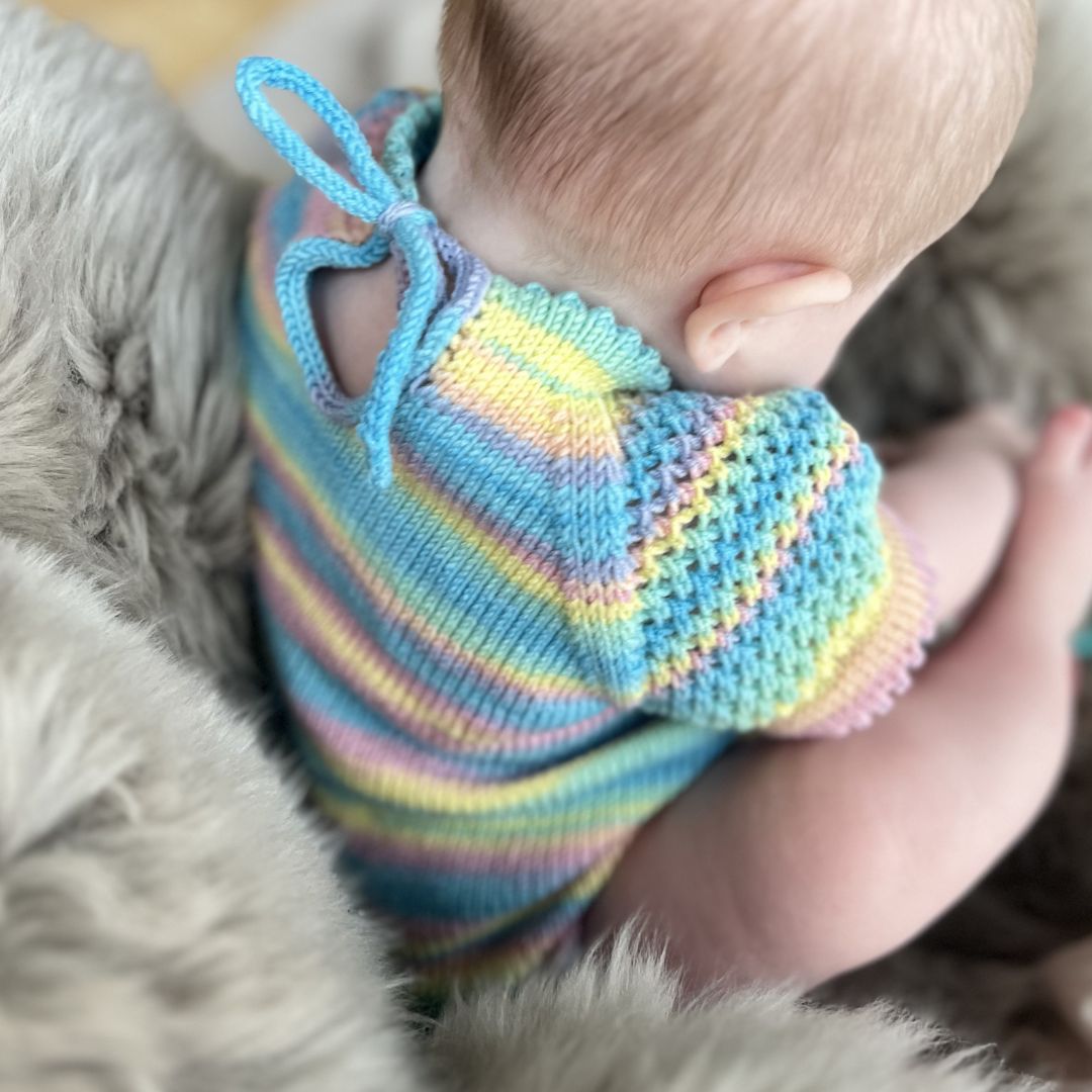 Knytting i nakken på strikket sommerbody – åpning som lufter godt i nakken. Strikkepakke sommerbody i 100% merinoull med romslig passform over rumpa. Strikke sommerbody til baby fra nyfødt til 2 år i Dale Garn Soft Merino.
