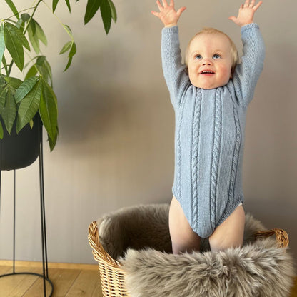 Vesleskattens flettebody – så stor! Strikkepakke baby i 100% kløfri merinoull med flettemønster. Elastisk hals, ingen knapper i halsen og knapper mellom beina for enkelt bleiebytt. Størrelser fra nyfødt til 2,5 år.