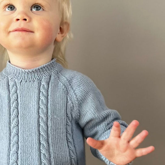 Detaljer på flettemønster i Vesleskattens flettebody – strikkepakke body i 100% kløfri merinoull. Elastisk hals og ingen knapper i halsen for enkel av og påkledning. Størrelser fra nyfødt til 2,5 år.