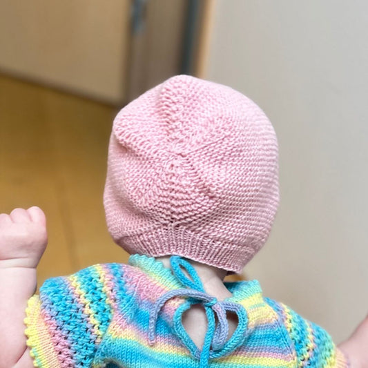 Vesleskattens rillekyse bakfra – babylue i 100% merinoull som ikke klør. Nybegynnervennlig og rask å strikke til baby eller nyfødt. Praktisk kyse i flere farger å velge mellom.